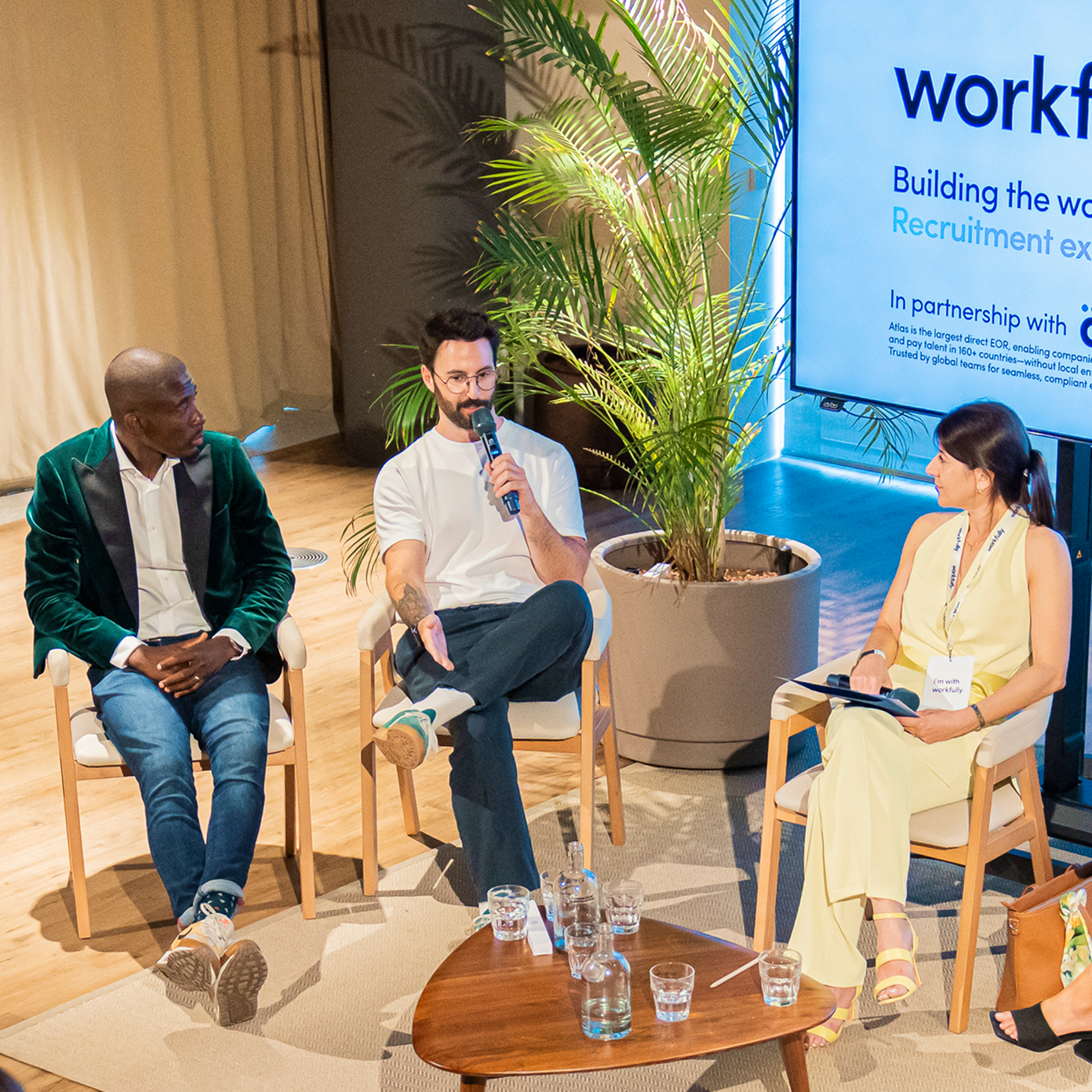 Speakers on stage at a Workfully panel discussion with branding on screen